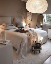 Zicht op een bed in slaapkamer met een grote witte hanglamp boven het bed